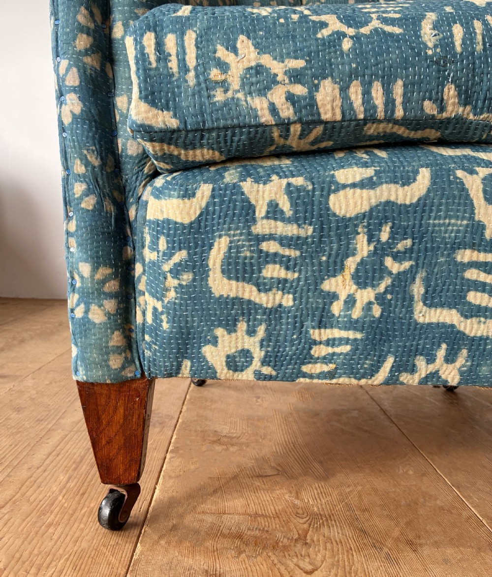 A 19th-century tub chair with blue and cream patterned fabric upholstery, button-tufted backrest, rolled arms, and tapered mahogany legs on brass castors. View II