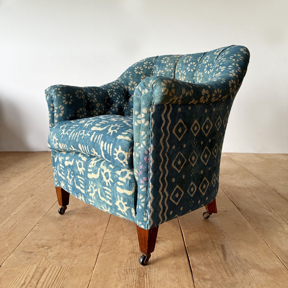 A 19th-century tub chair with blue and cream patterned fabric upholstery, button-tufted backrest, rolled arms, and tapered mahogany legs on brass castors. View III