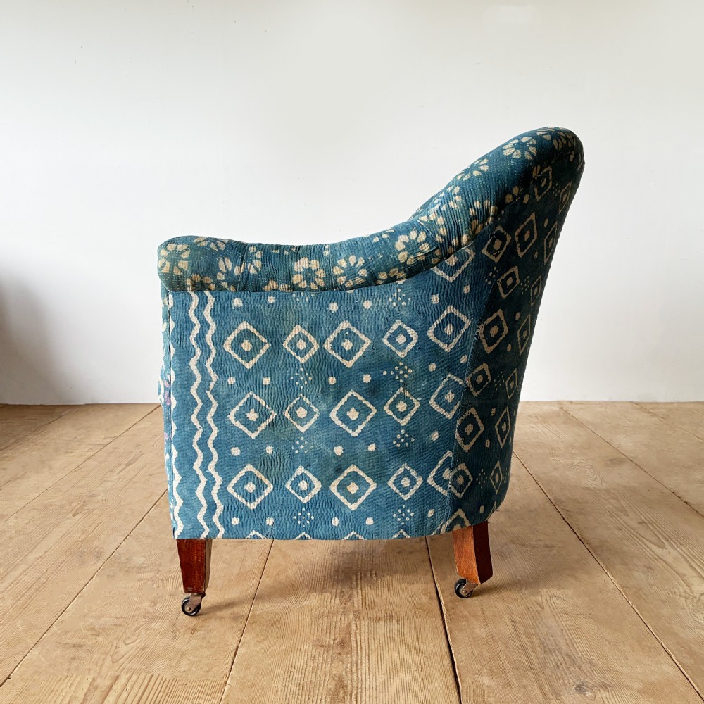 A 19th-century tub chair with blue and cream patterned fabric upholstery, button-tufted backrest, rolled arms, and tapered mahogany legs on brass castors. View IV