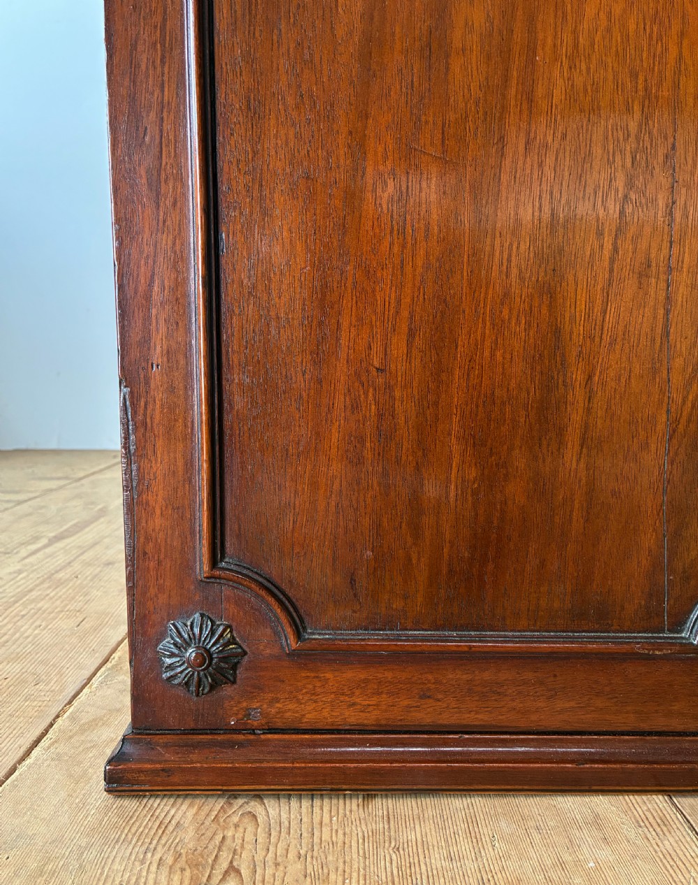 A George II mahogany wall cabinet featuring a carved swan-neck pediment and panelled twin doors with rosette corner accents. View II