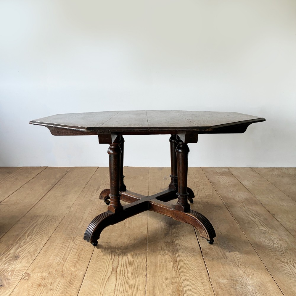 A dark oak Reformed Gothic table with an octagonal top set upon four turned columns and a quadripartite base with castors.
