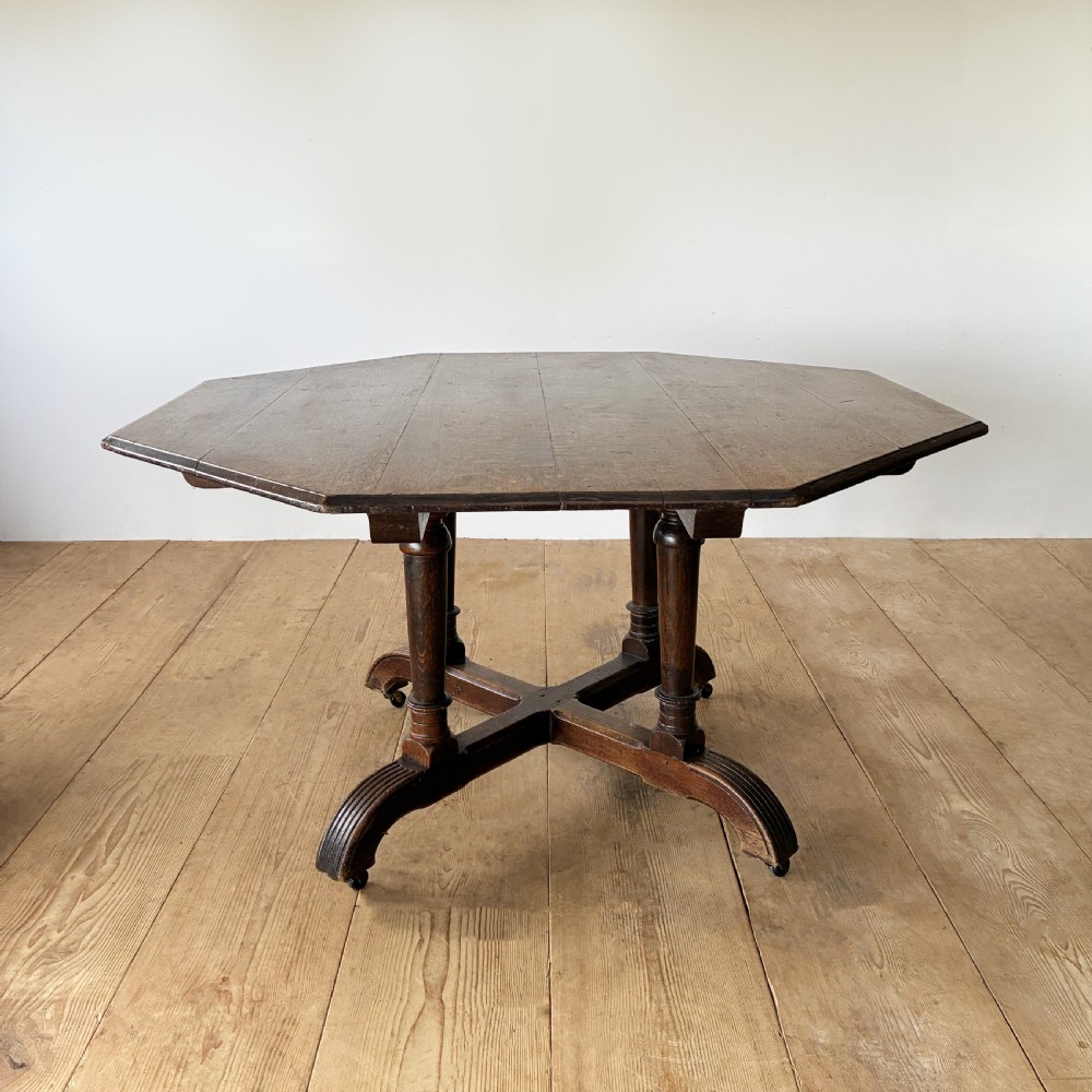 A dark oak Reformed Gothic table with an octagonal top set upon four turned columns and a quadripartite base with castors. View III