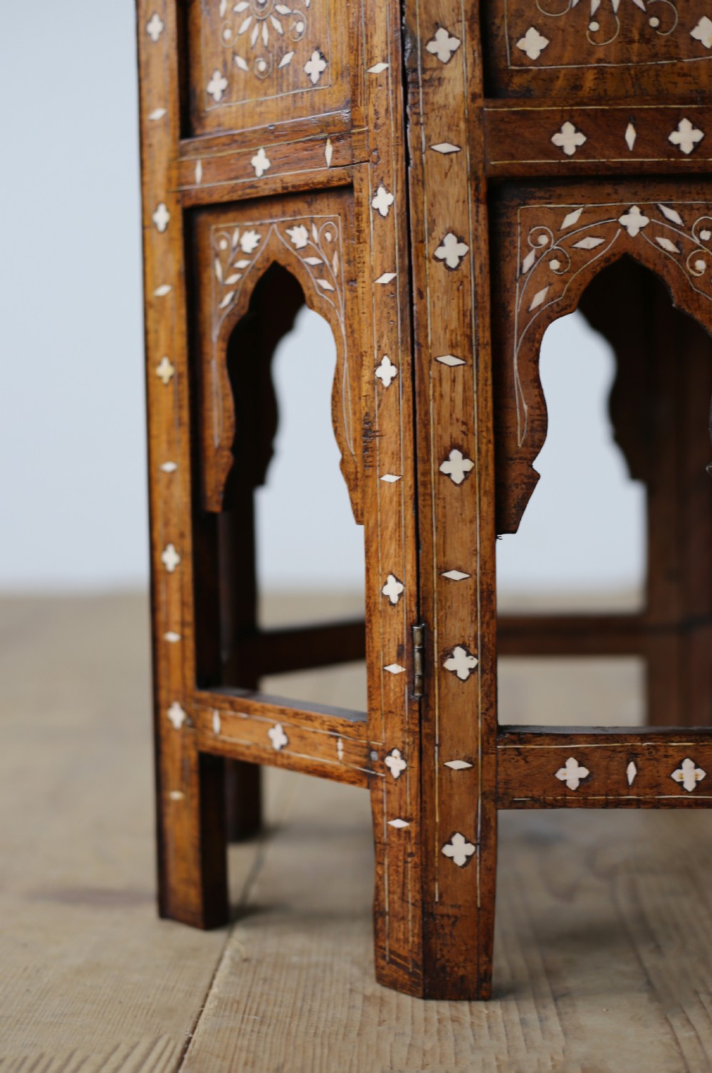 A 19th-century octagonal wooden side table with detailed white bone inlay forming floral and geometric patterns across the top and arched legs. View II