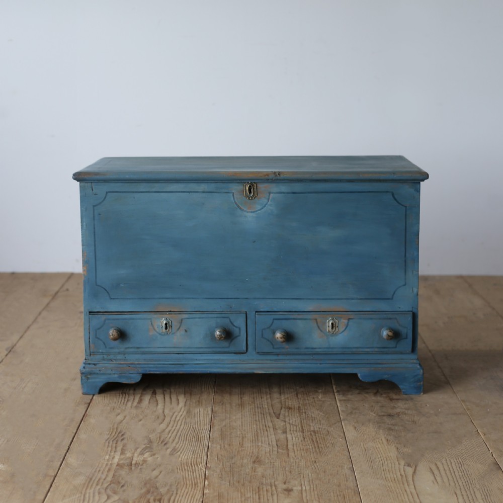 A 19th-century rustic slate blue painted wooden mule chest with a hinged lid top and two drawers with wooden knobs at the base.