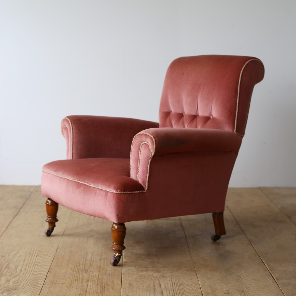 A 19th-century armchair upholstered in dusky rose pink velvet with a buttoned backrest, scroll arms, and turned wooden front legs set on castors. View II
