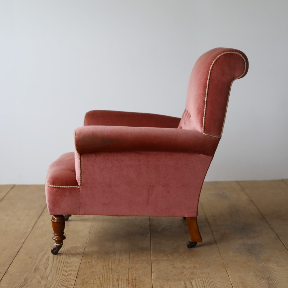 A 19th-century armchair upholstered in dusky rose pink velvet with a buttoned backrest, scroll arms, and turned wooden front legs set on castors. View IV