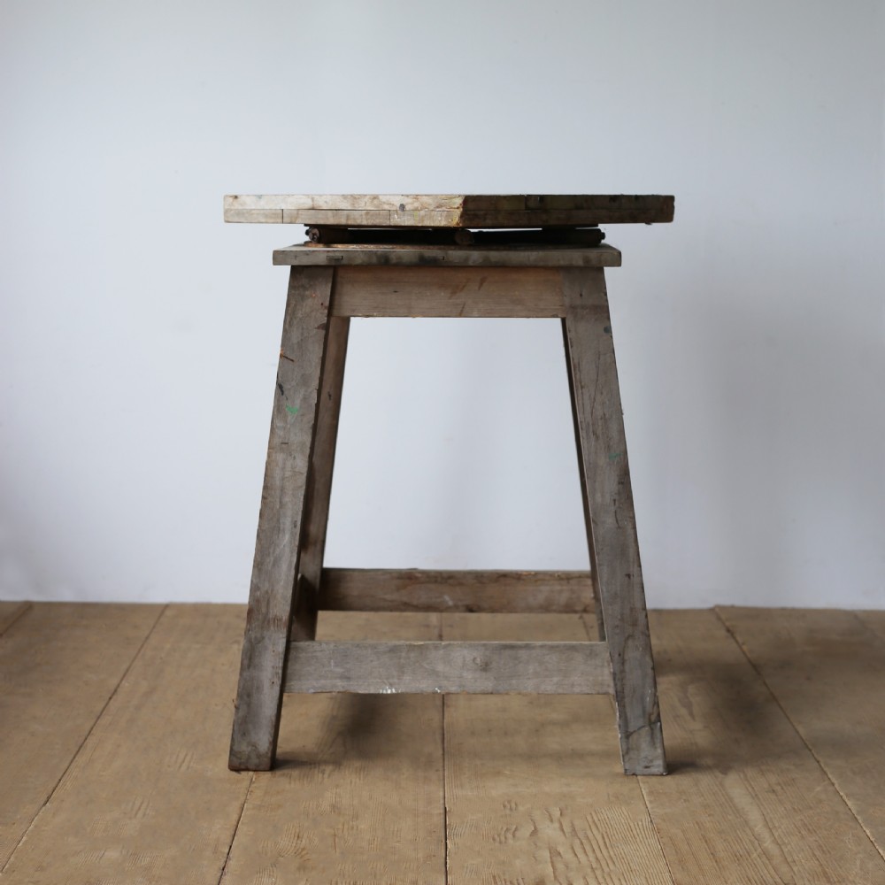 A 19th-century weathered wooden sculptors stand featuring a square revolving top supported by four tapered legs and cross-stretchers.