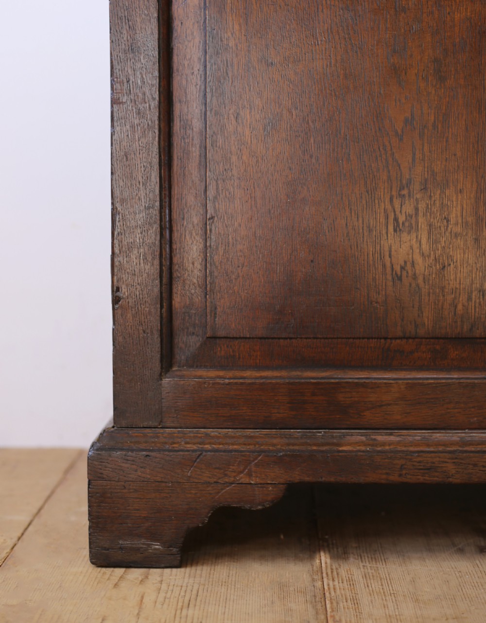 A tall George III dark oak glazed bookcase featuring two upper glass panelled doors over a double cupboard base supported by bracket feet. View III
