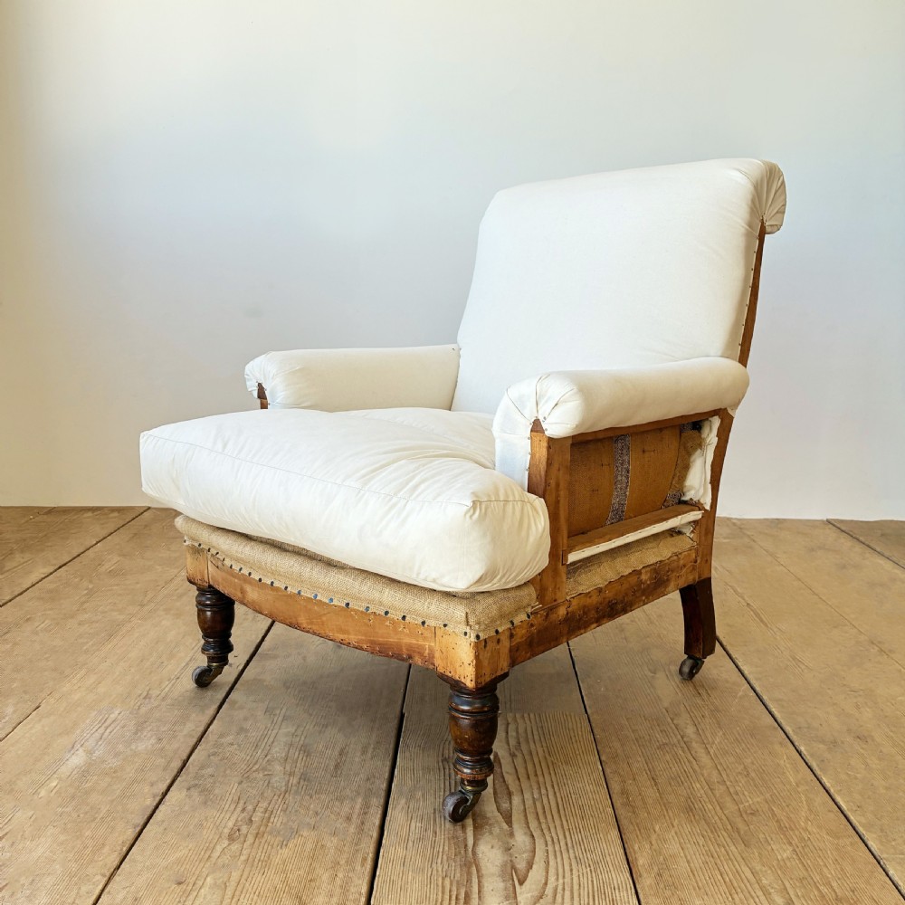 A nineteenth century Howard style armchair with cream calico fabric, deep seat cushion, scrolled arms, and turned timber legs on brass castors. View III