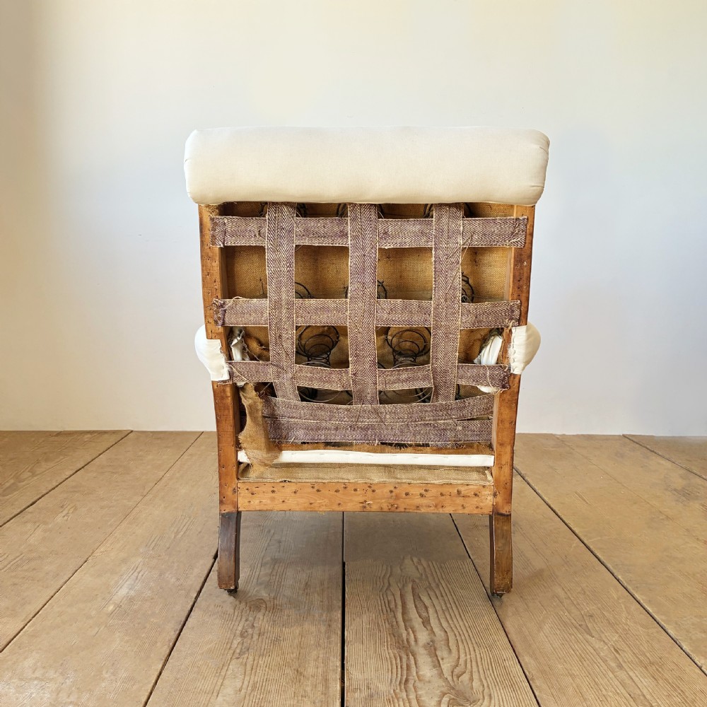 A nineteenth century Howard style armchair with cream calico fabric, deep seat cushion, scrolled arms, and turned timber legs on brass castors. View V