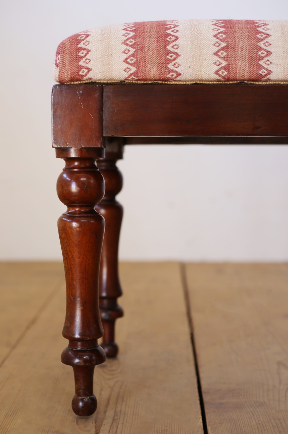 A long rectangular 19th-century window seat featuring a red and cream striped upholstered cushion set upon four turned dark hardwood legs. View III