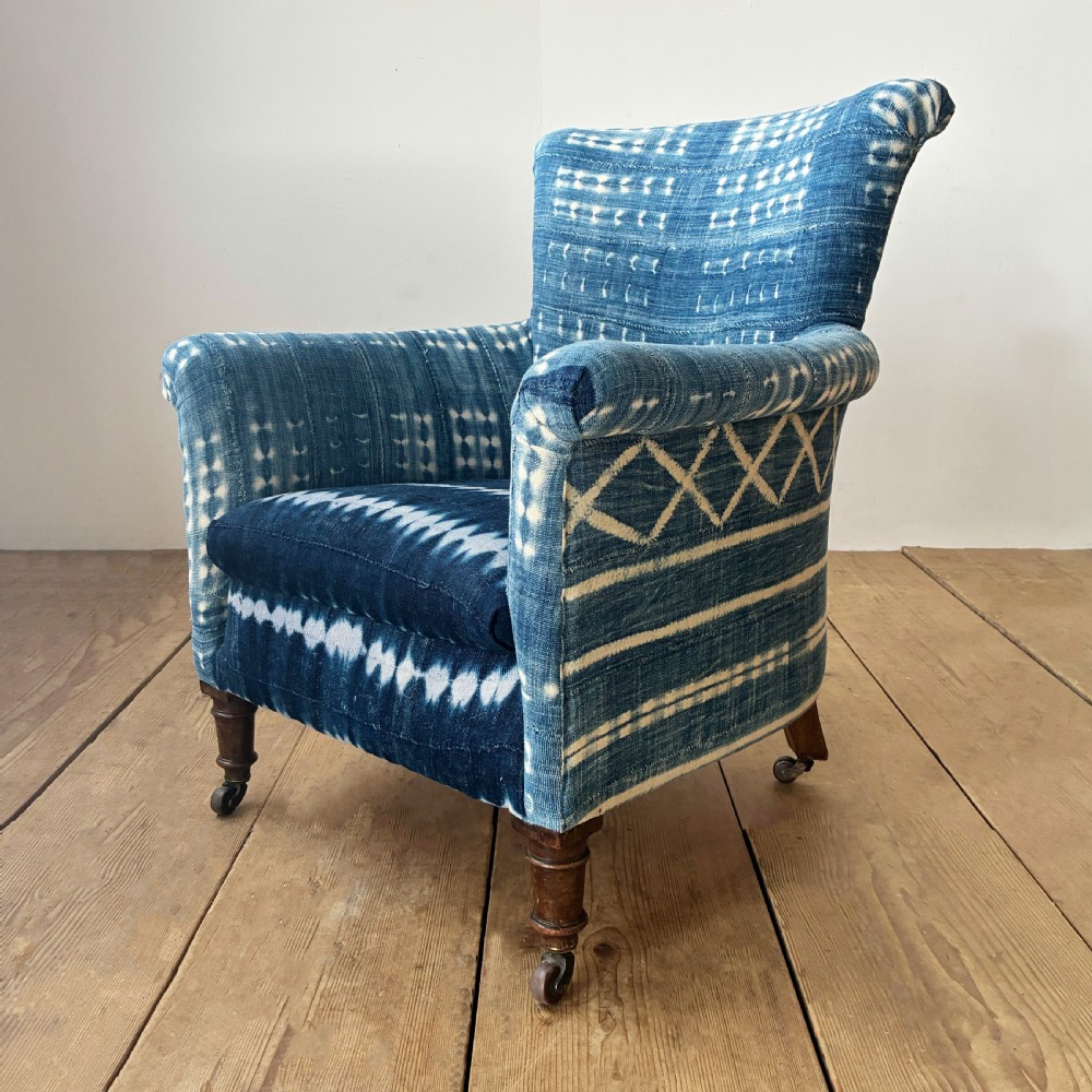 A 19th-century Woodstock armchair upholstered in indigo blue pattern-dyed cotton fabric, featuring scroll arms and turned wood legs on castors. View III