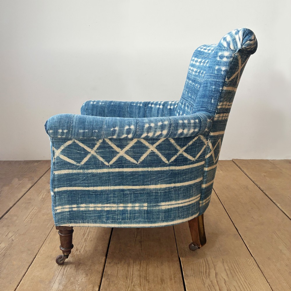 A 19th-century Woodstock armchair upholstered in indigo blue pattern-dyed cotton fabric, featuring scroll arms and turned wood legs on castors. View IV