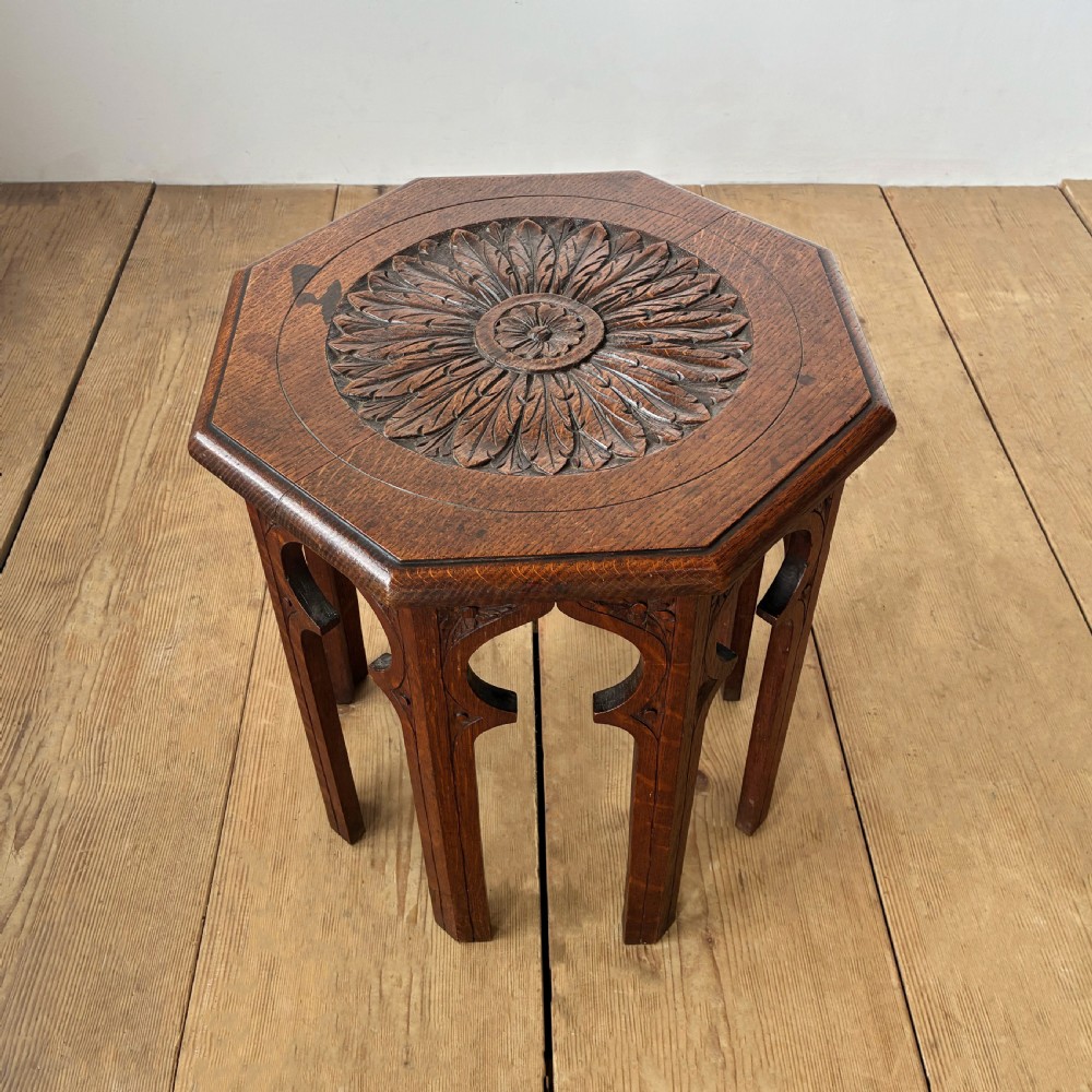 An octagonal 19th-century oak side table featuring a central carved foliate rosette top and arched Moorish revival legs.