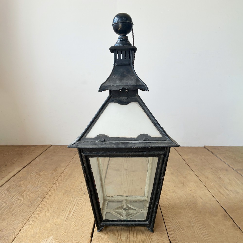 A black metal 19th-century lantern featuring clear glass panes, a tapered body, and a tiered pagoda-style canopy topped with a round finial. View II