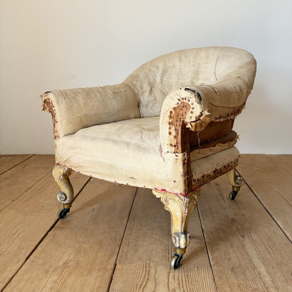 A 19th-century tub chair upholstered in natural calico fabric with carved giltwood cabriole front legs on metal castors. View III