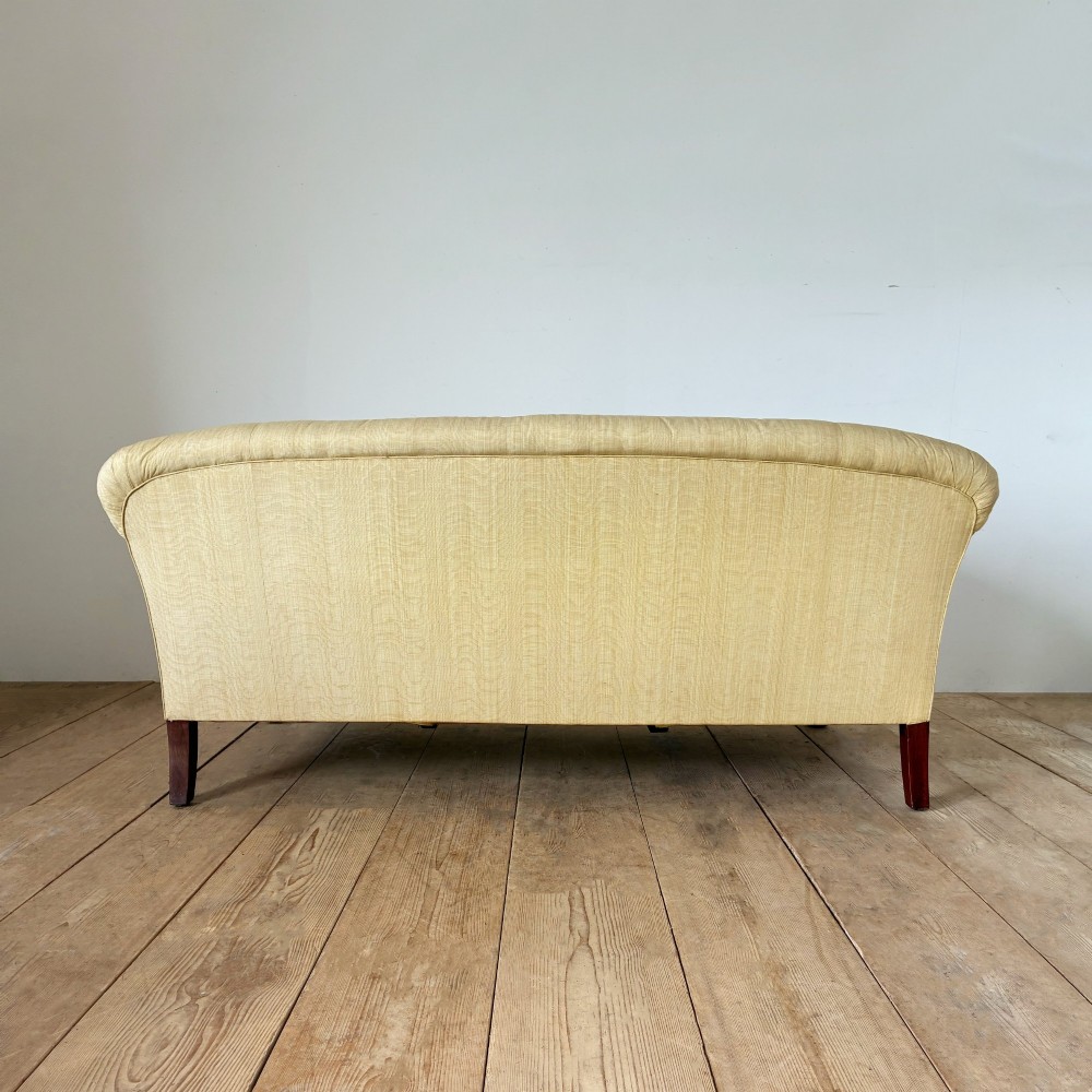 An upholstered two-seater sofa in yellow fabric featuring low scrolled arms, deep seat cushions, and carved dark mahogany cabriole legs with claw and ball feet. View II