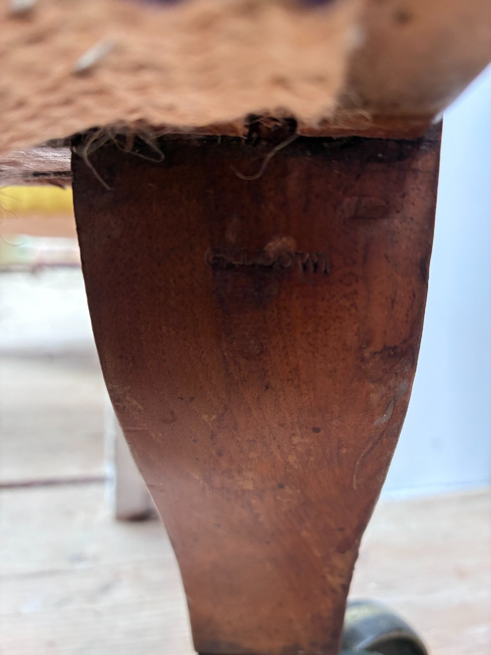 A nineteenth-century armchair frame in calico and hessian under-upholstery, featuring carved turned wooden front legs with metal castors. View VI