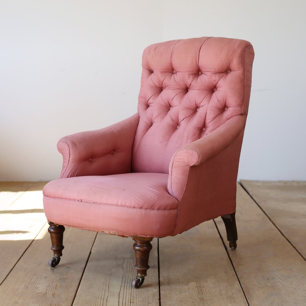 A 19th-century Victorian armchair upholstered in dusty rose fabric featuring a deep button back, padded armrests, and turned legs on brass castors. View III