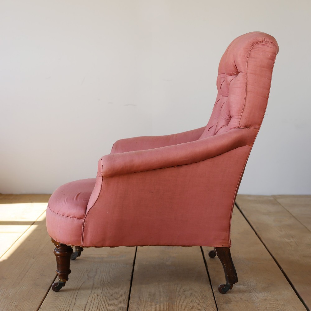 A 19th-century Victorian armchair upholstered in dusty rose fabric featuring a deep button back, padded armrests, and turned legs on brass castors. View IV