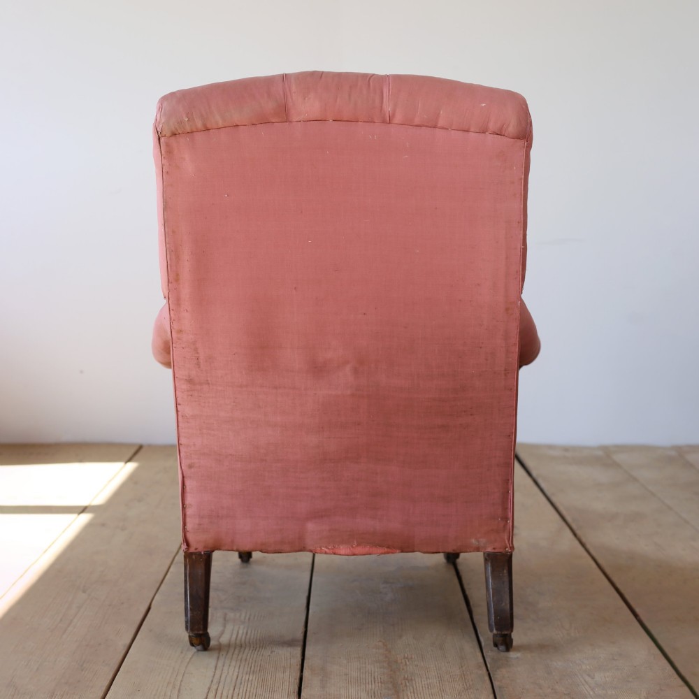 A 19th-century Victorian armchair upholstered in dusty rose fabric featuring a deep button back, padded armrests, and turned legs on brass castors. View V