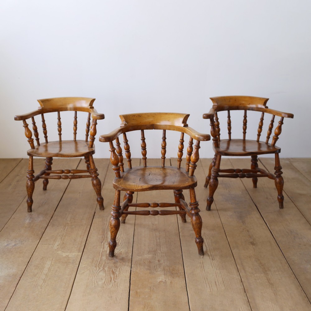 A set of twelve 19th-century wooden smokers bow armchairs featuring horseshoe crest rails, turned spindles, saddle seats, and stretcher-bound turned legs. View III