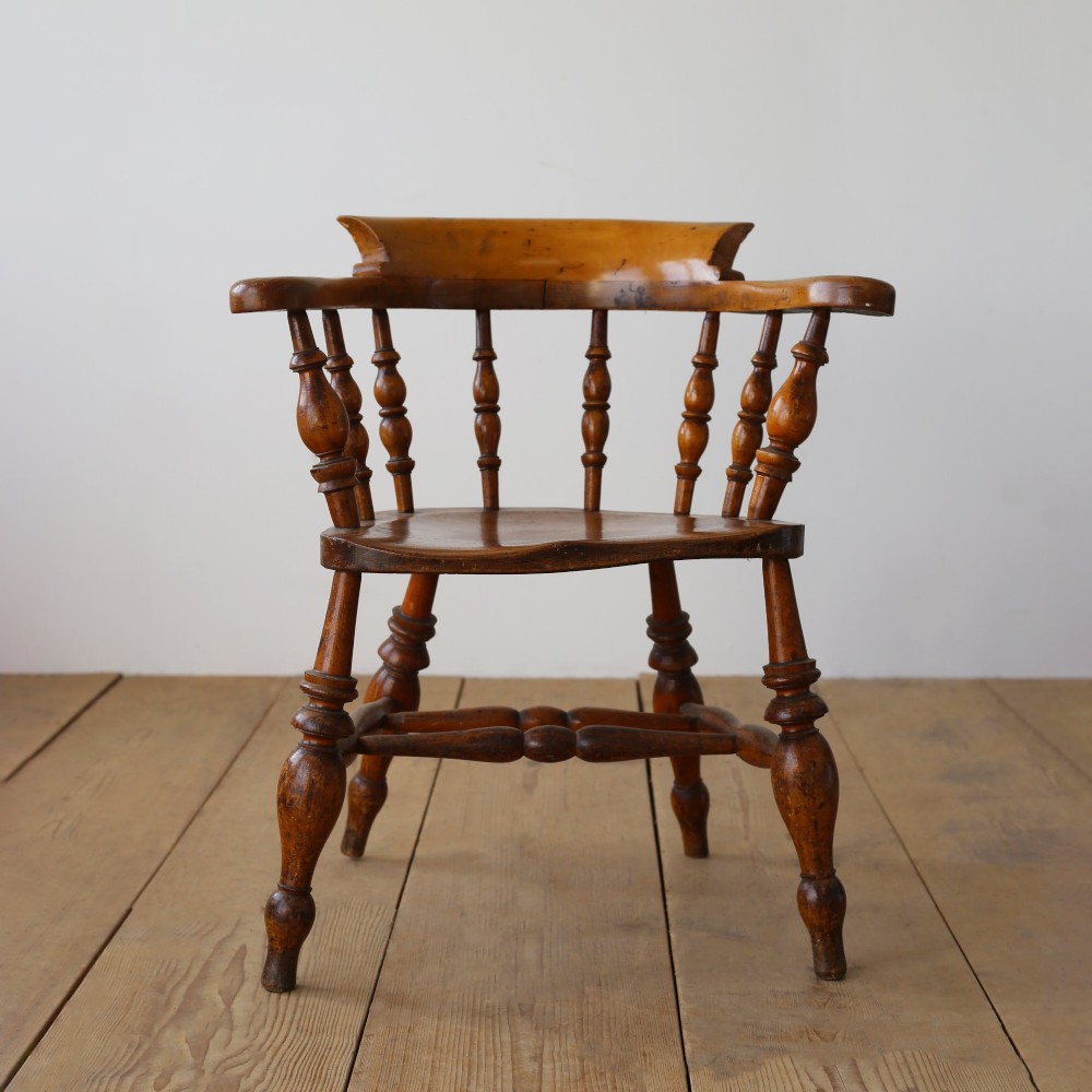 A set of twelve 19th-century wooden smokers bow armchairs featuring horseshoe crest rails, turned spindles, saddle seats, and stretcher-bound turned legs. View IV