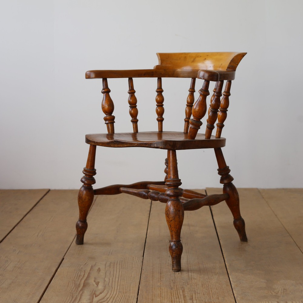 A set of twelve 19th-century wooden smokers bow armchairs featuring horseshoe crest rails, turned spindles, saddle seats, and stretcher-bound turned legs. View V