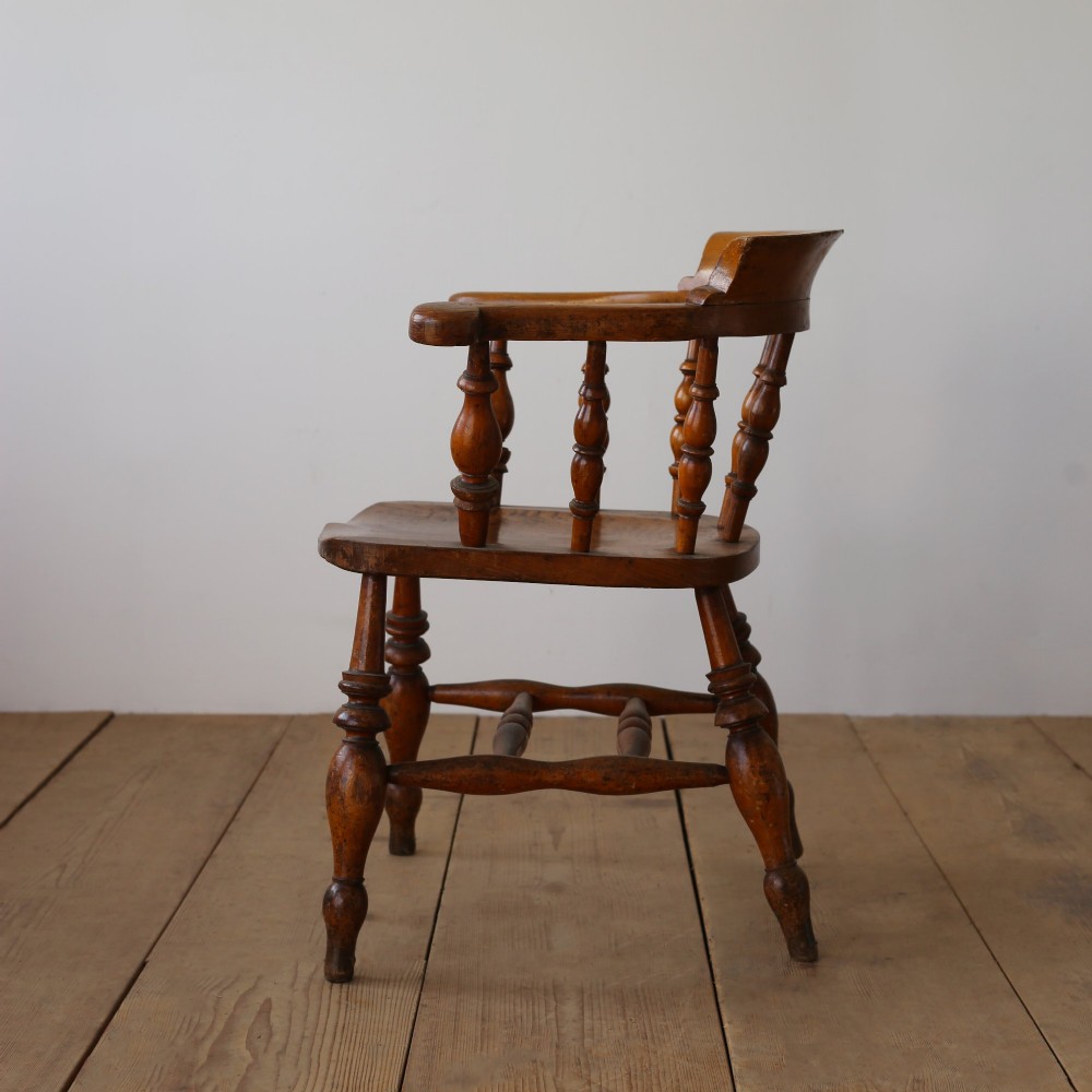 A set of twelve 19th-century wooden smokers bow armchairs featuring horseshoe crest rails, turned spindles, saddle seats, and stretcher-bound turned legs. View VI