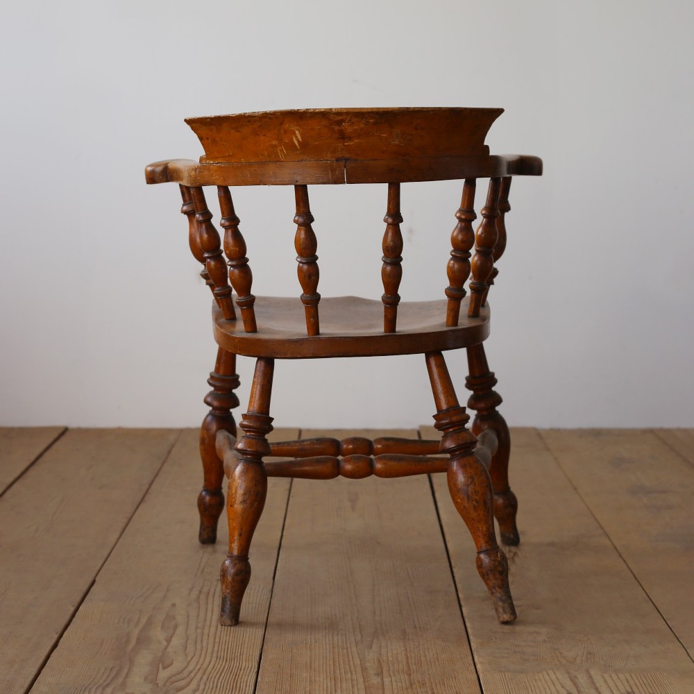 A set of twelve 19th-century wooden smokers bow armchairs featuring horseshoe crest rails, turned spindles, saddle seats, and stretcher-bound turned legs. View VII
