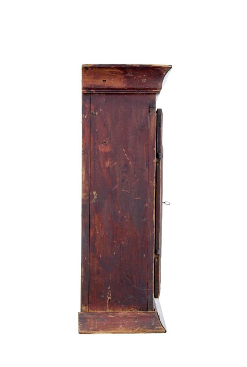 fig 1. An early 19th-century Swedish painted pine wall cupboard featuring double panelled doors in a terracotta finish with moulded borders and central iron lock plate.