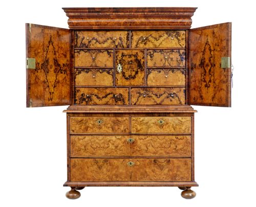 fig 2. An 18th-century George I burr walnut cabinet on chest featuring double upper doors, brass keyhole escutcheons, and turned bun feet.