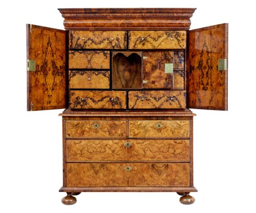 fig 3. An 18th-century George I burr walnut cabinet on chest featuring double upper doors, brass keyhole escutcheons, and turned bun feet.