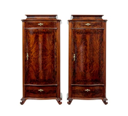 fig 1. A pair of 19th-century Scandinavian tall mahogany cupboards featuring serpentine fronts, flame veneer panels, and ornate brass keyhole escutcheons.