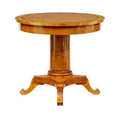 fig 1. A late 19th-century Swedish circular centre table in golden satin birch veneer, featuring ebonised inlay, a cylindrical pedestal column, and a four-point plinth with scroll feet.