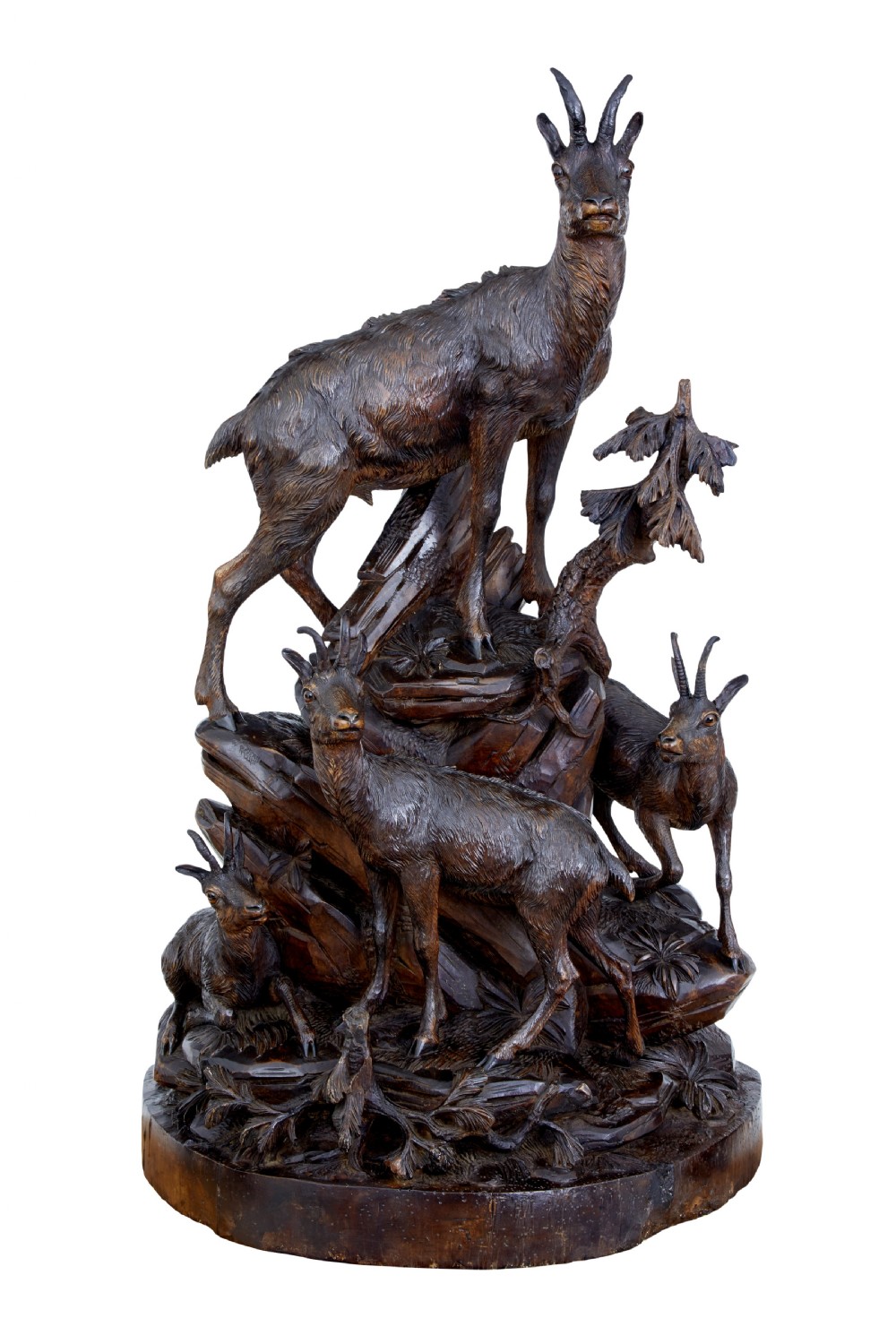A detailed 19th-century hand-carved linden wood sculpture featuring an alpine ibex standing on a rocky outcrop surrounded by smaller goats.