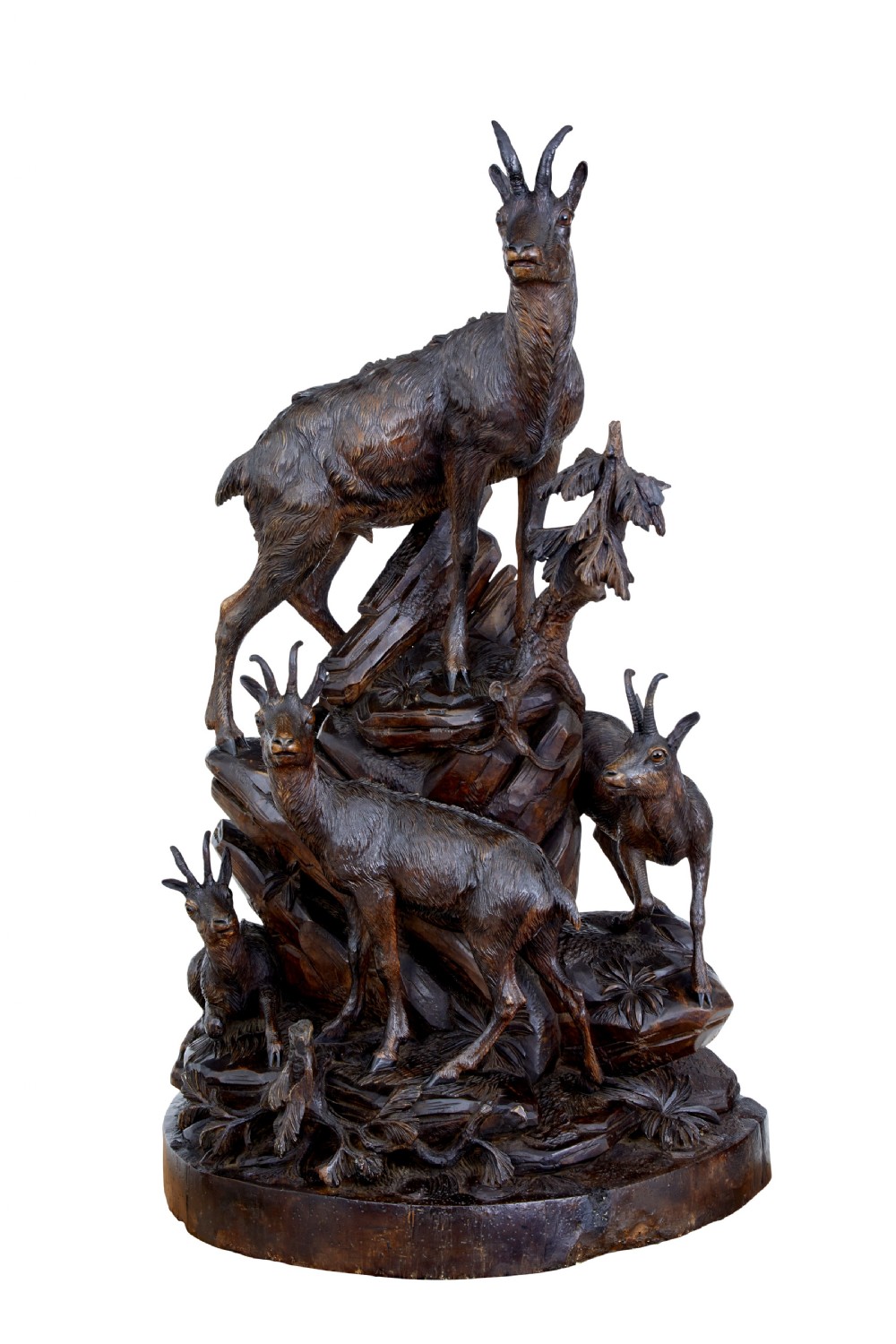 A detailed 19th-century hand-carved linden wood sculpture featuring an alpine ibex standing on a rocky outcrop surrounded by smaller goats. View VII