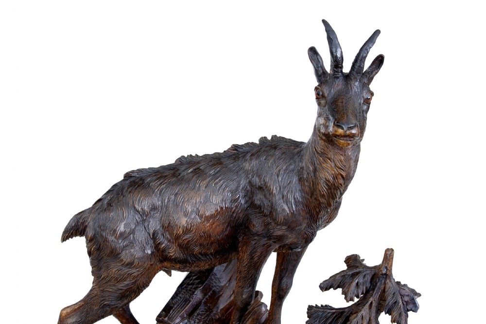 A detailed 19th-century hand-carved linden wood sculpture featuring an alpine ibex standing on a rocky outcrop surrounded by smaller goats. View IX