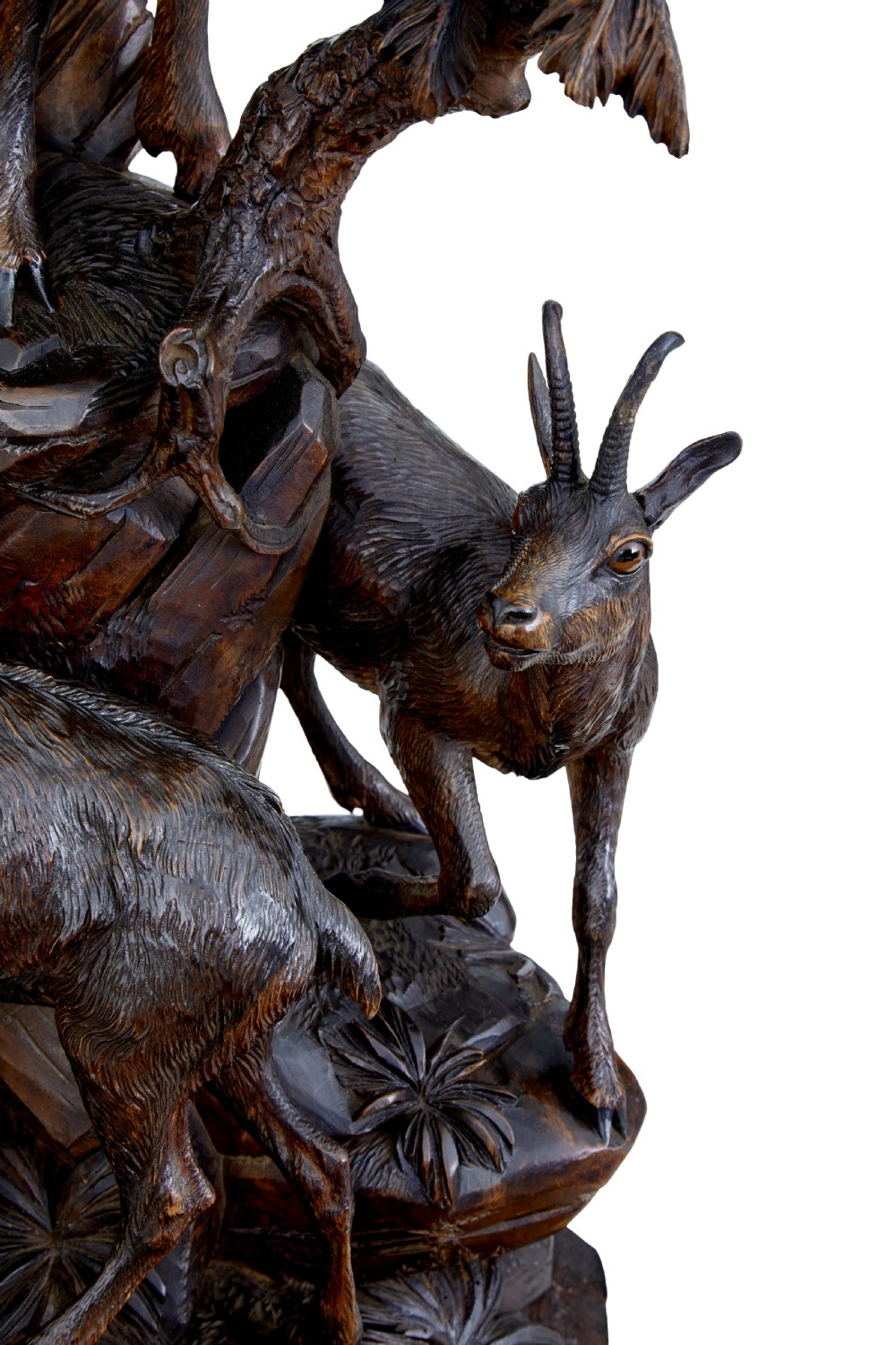 A detailed 19th-century hand-carved linden wood sculpture featuring an alpine ibex standing on a rocky outcrop surrounded by smaller goats. View X