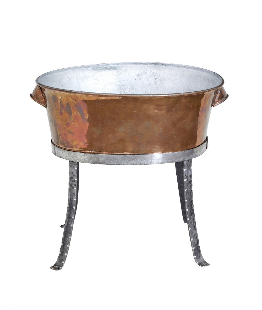 An oval copper basin with a silver-coloured lining and side handles, elevated on a four-legged hammered wrought iron stand. View II