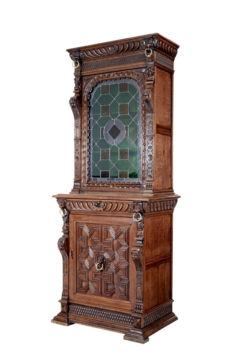 A tall 19th-century Flemish oak cabinet featuring an upper arched leaded glass door and a lower geometric carved wooden door.