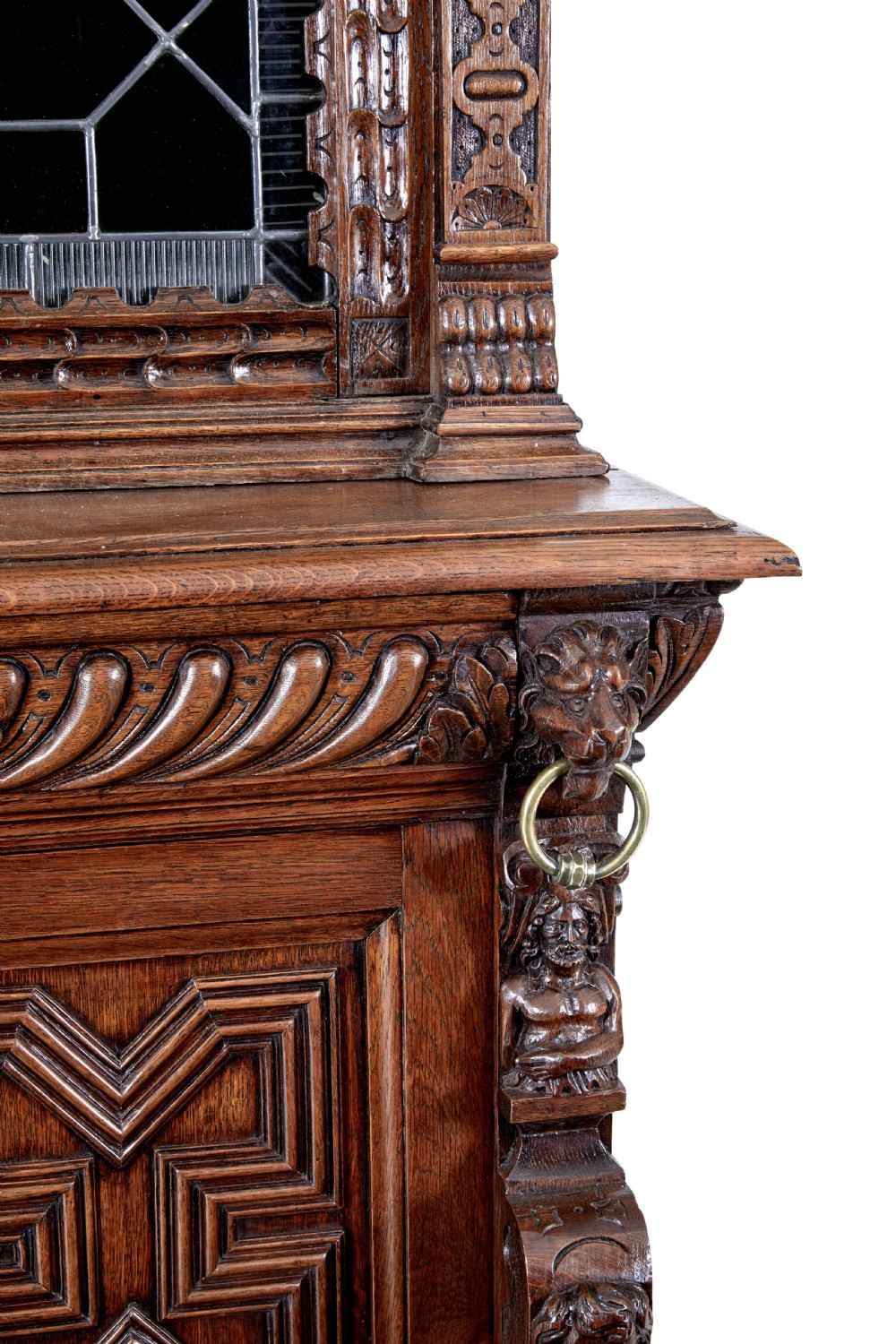 A tall 19th-century Flemish oak cabinet featuring an upper arched leaded glass door and a lower geometric carved wooden door. View VII