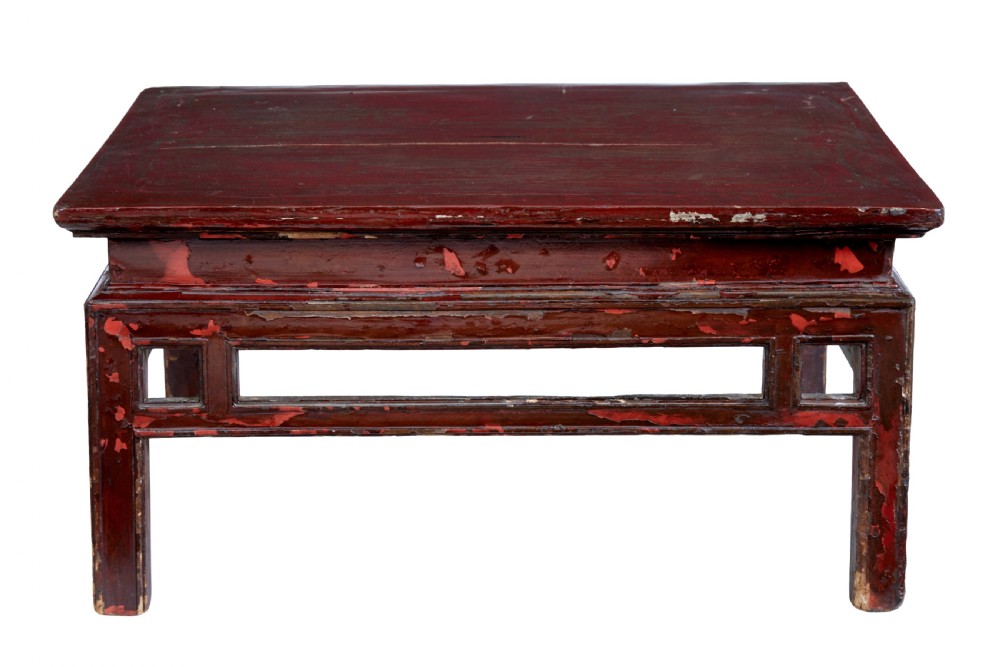 An 18th-century Chinese low table featuring a distressed red lacquer finish, straight square legs, and geometric openwork aprons. View V
