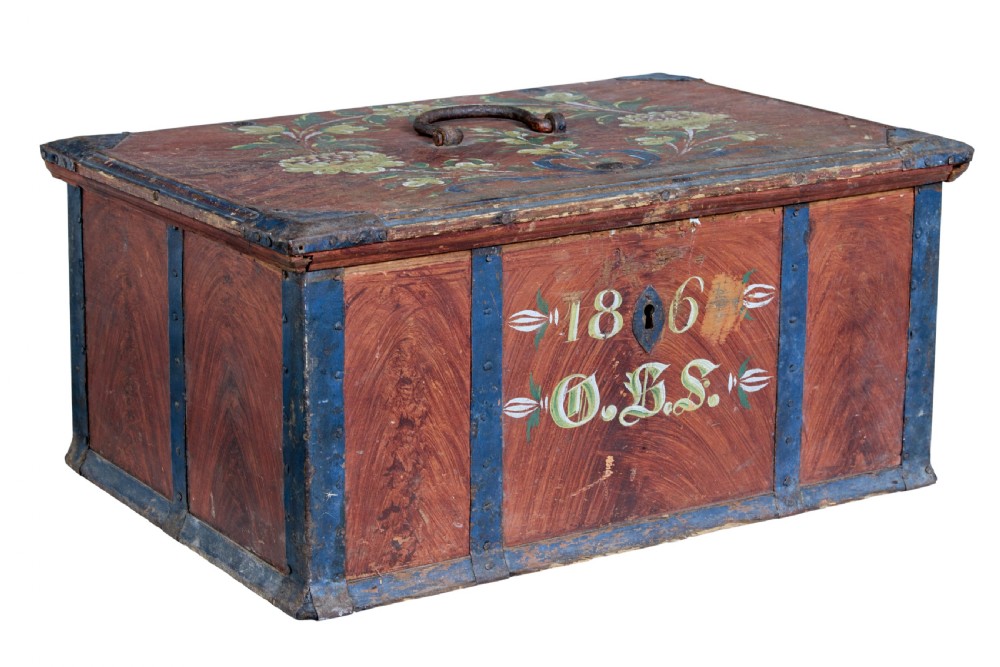 An antique rectangular Swedish wooden box featuring a reddish brown finish with blue painted metal corner straps, a floral lid design, and the painted date 1806.