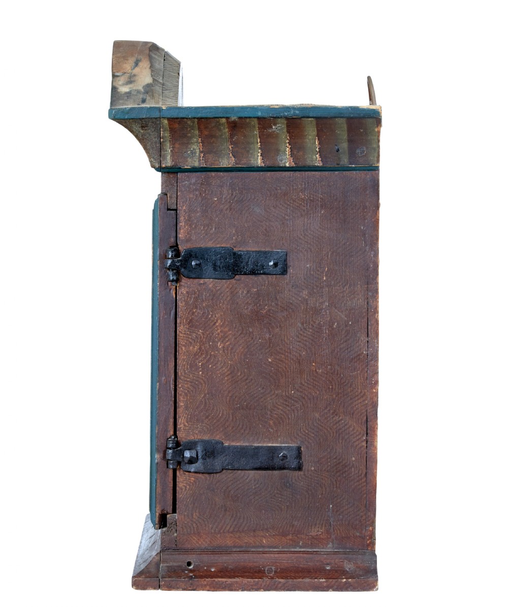 An early 19th-century Swedish painted wall cupboard featuring an arched crest, dark teal trim, and painted floral motifs in terracotta and ochre with the date 1822. View VI