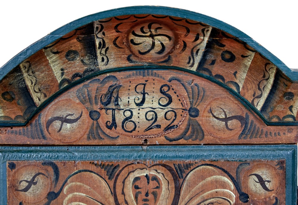 An early 19th-century Swedish painted wall cupboard featuring an arched crest, dark teal trim, and painted floral motifs in terracotta and ochre with the date 1822. View VII