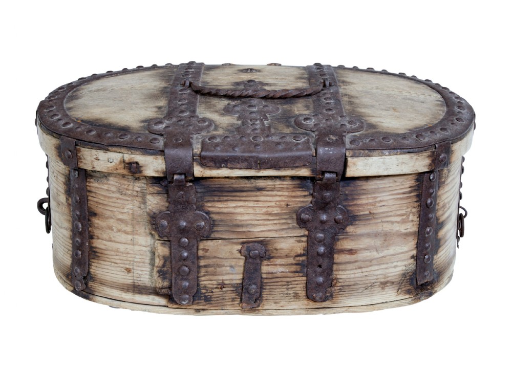 An oval Swedish pine box featuring decorative wrought iron straps, stud detailing, a central keyhole escutcheon, and a top twisted iron handle. View V