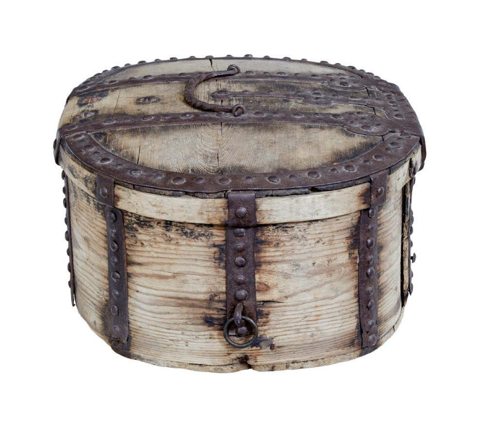 An oval Swedish pine box featuring decorative wrought iron straps, stud detailing, a central keyhole escutcheon, and a top twisted iron handle. View VI
