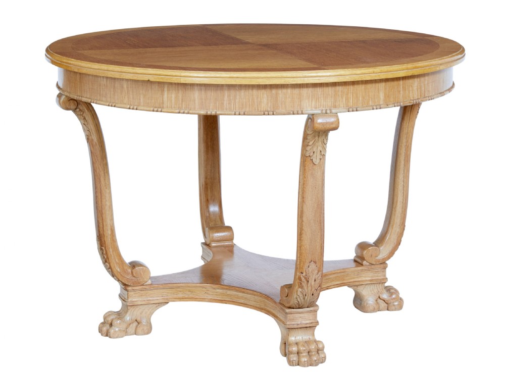A circular oak occasional table with a parquetry top, carved legs, and paw feet on a white background.