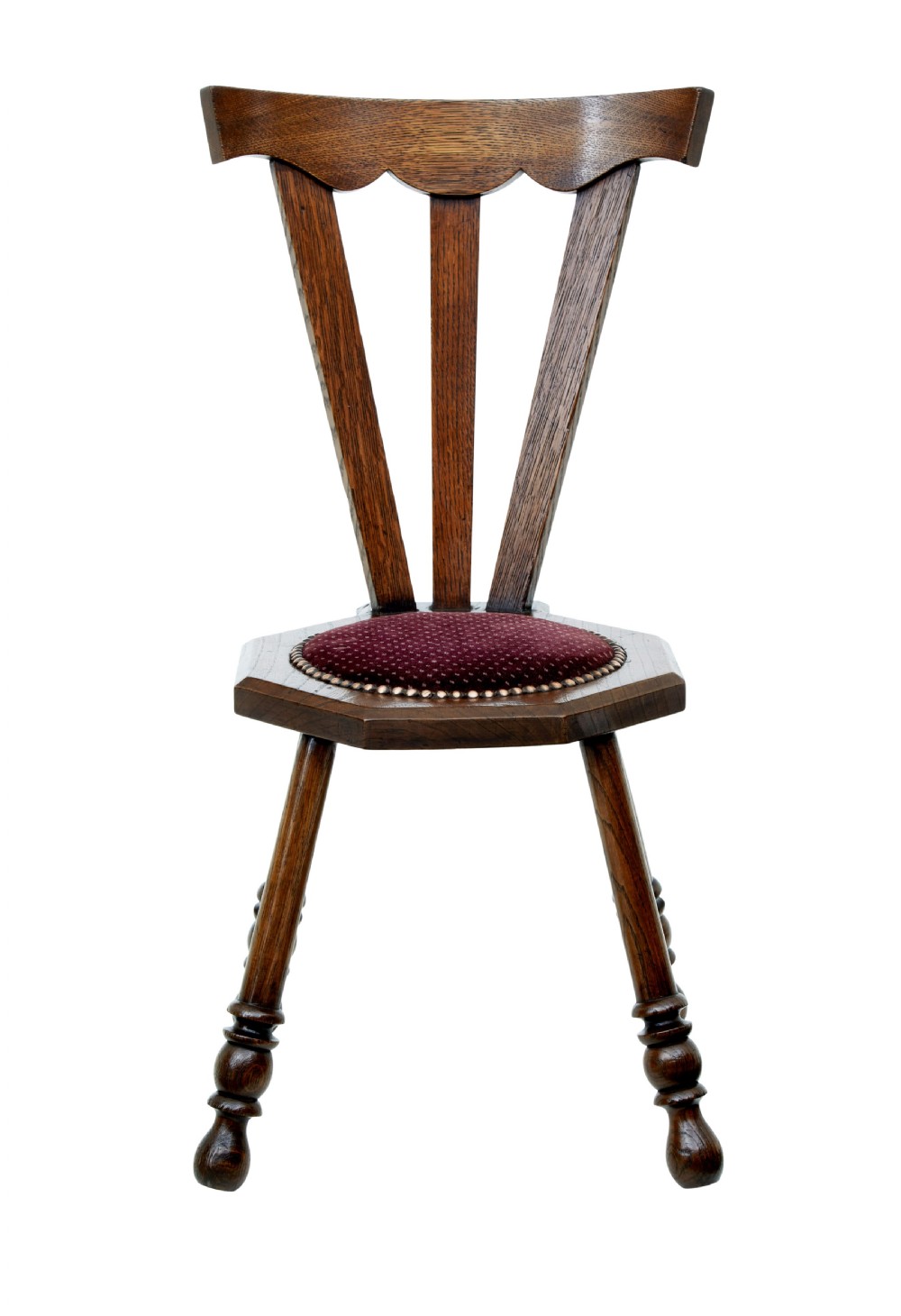 An early 20th-century Arts and Crafts oak childs chair featuring a sculpted top rail, three back splats, a hexagonal seat with red velvet upholstery, and turned splayed legs. View II